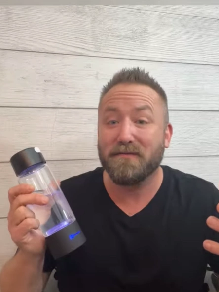 Person holding a clear bottle with a black lid.