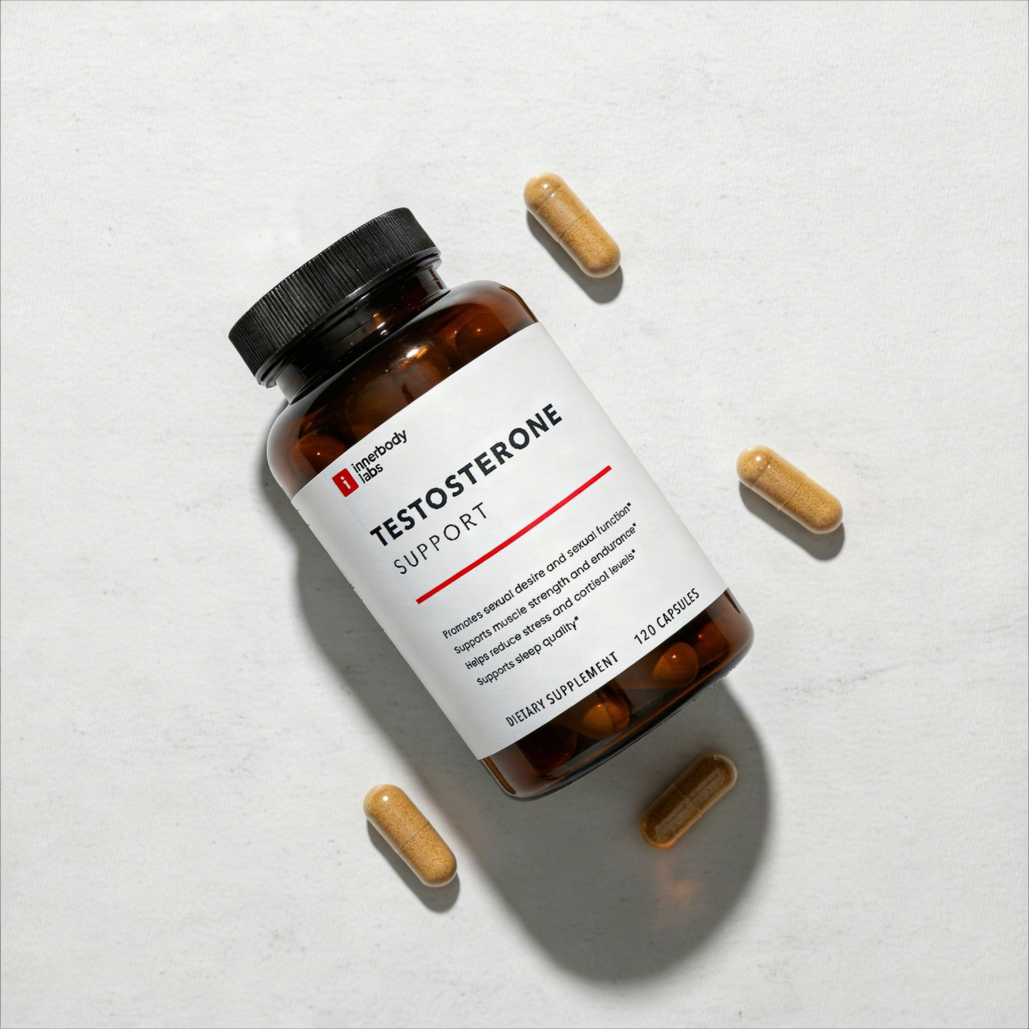 An overhead shot of a bottle of Testosterone Support supplements with loose capsules on a light background.