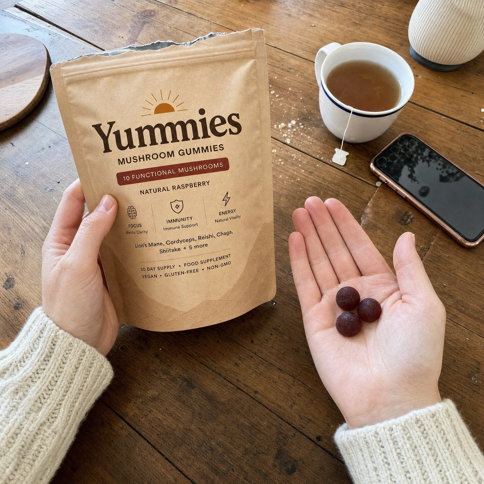 A person holding a bag of Yummies Mushroom Gummies and three gummies in their palm over a table.