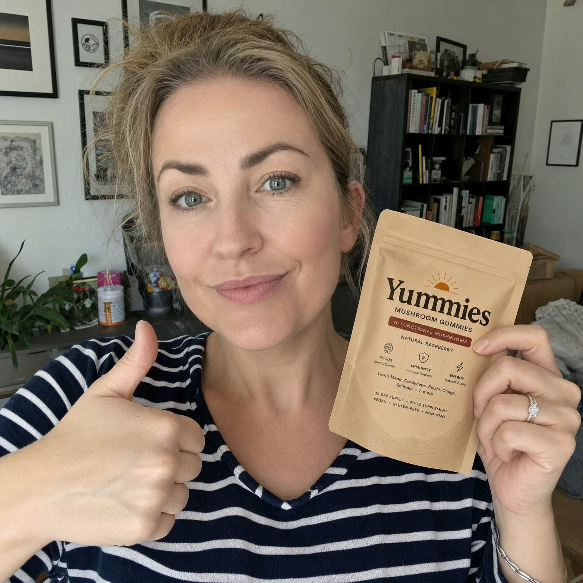 A woman holds a pouch of Yummies Mushroom Gummies and gives a thumbs-up to the camera.