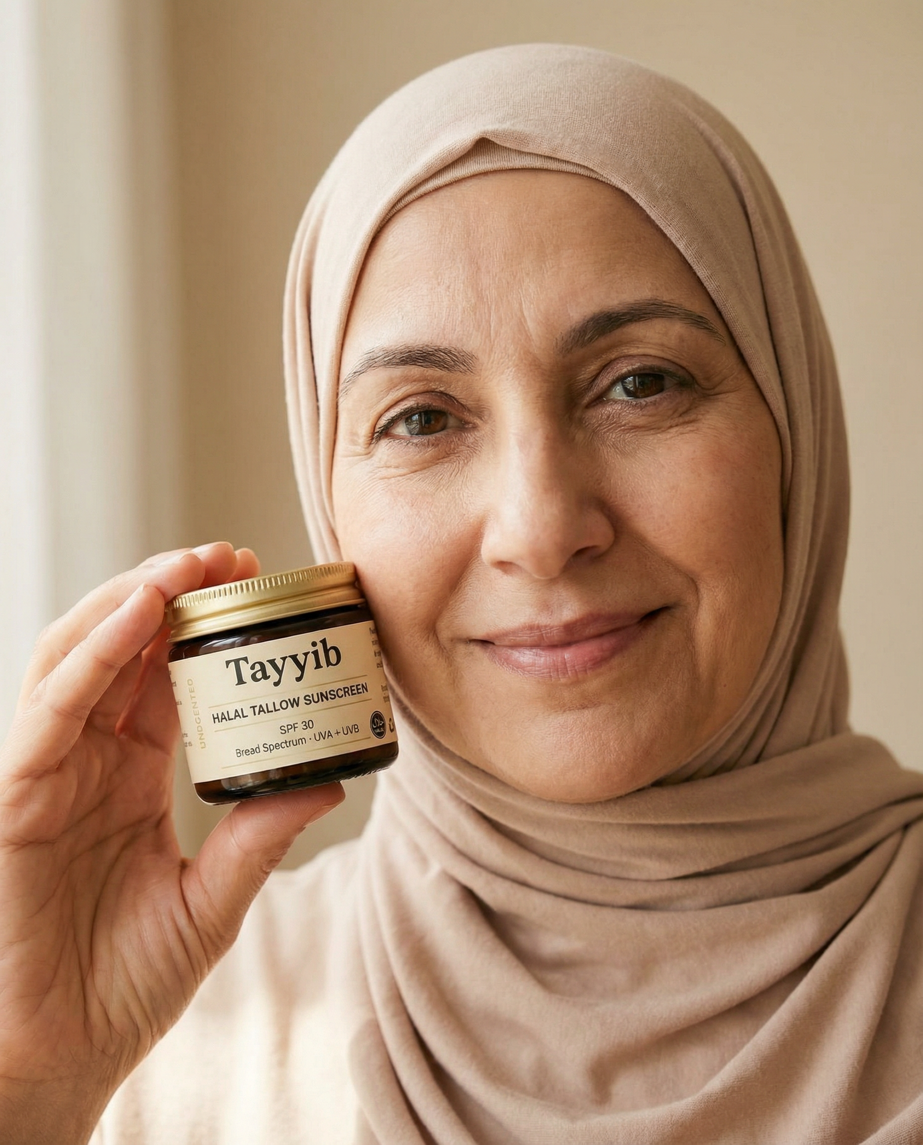 Person holding a jar of halāl tallow sunscreen, smiling.