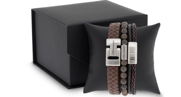 A black box containing two bracelets and a leather pouch, arranged neatly for display.