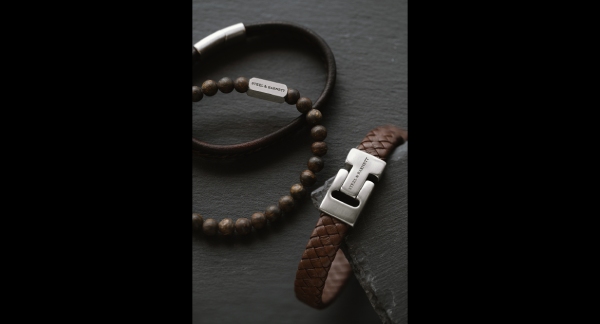 A black box containing two bracelets and a leather pouch, arranged neatly for display.