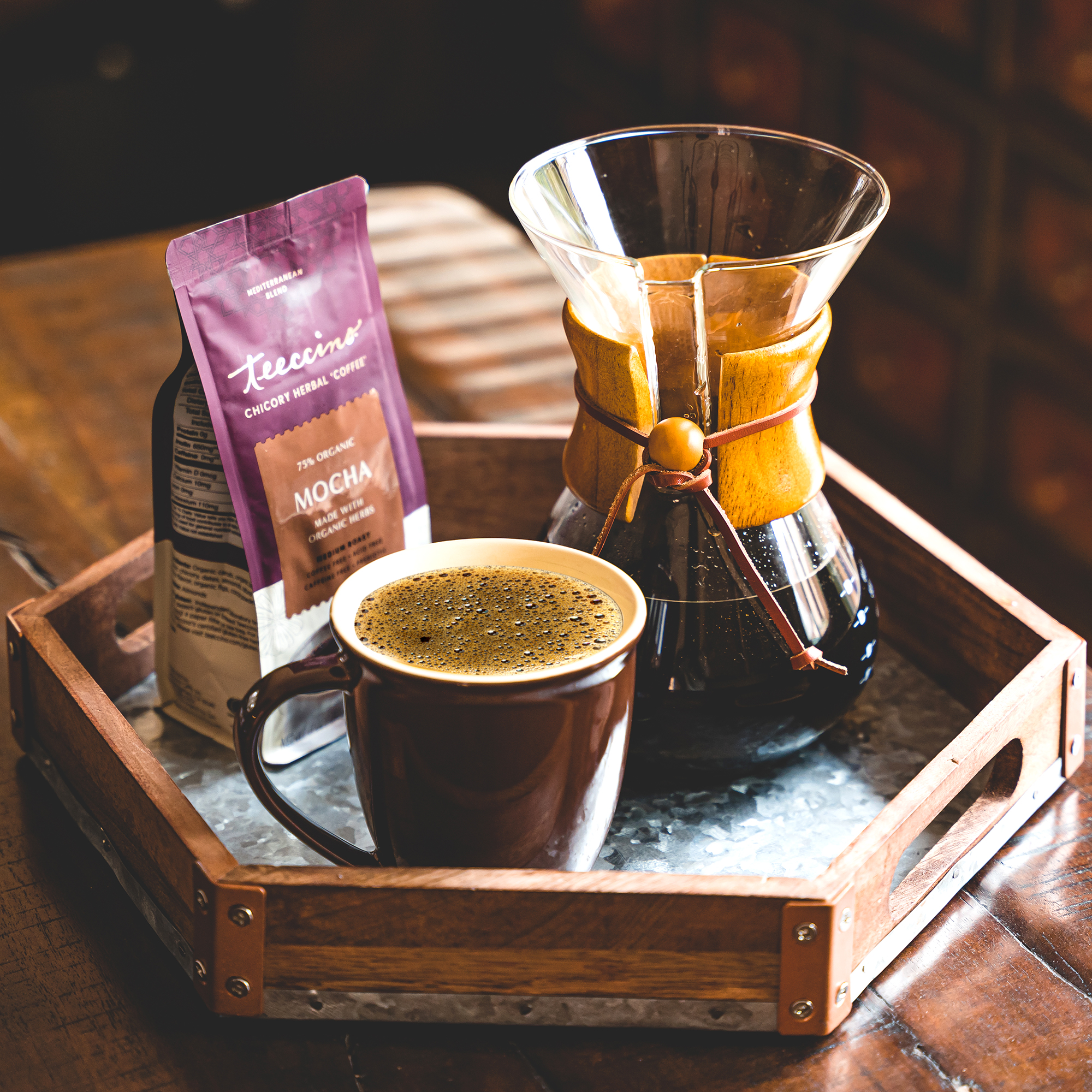 Coffee set with a mug, chemex, and coffee packet on a wooden tray.