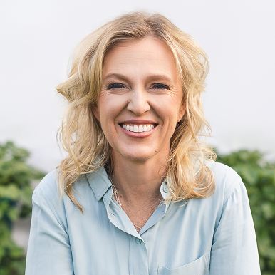 A person smiling outdoors in a light blue shirt.