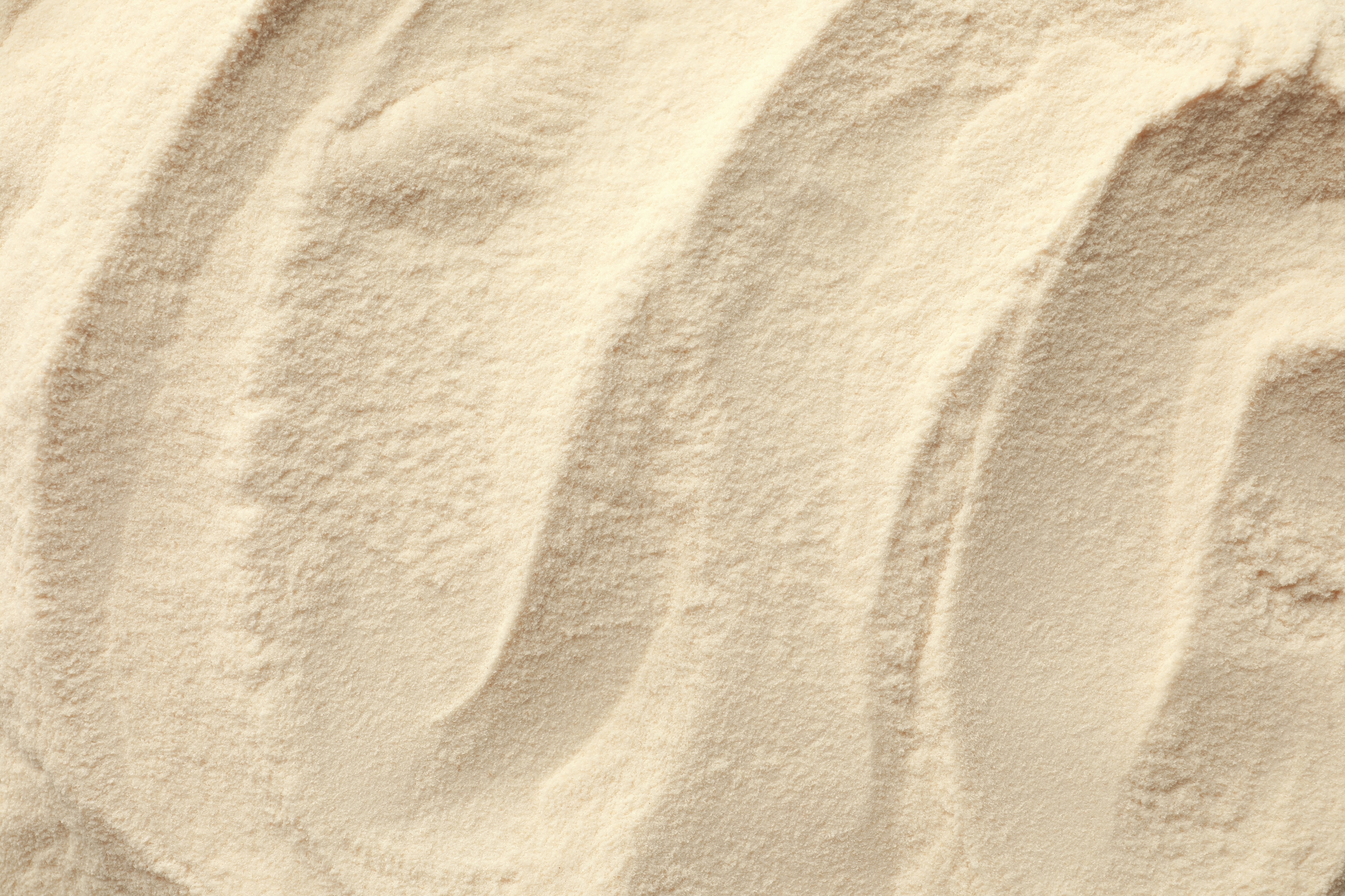 Close-up of fine, textured cream-colored powder with swirling patterns.