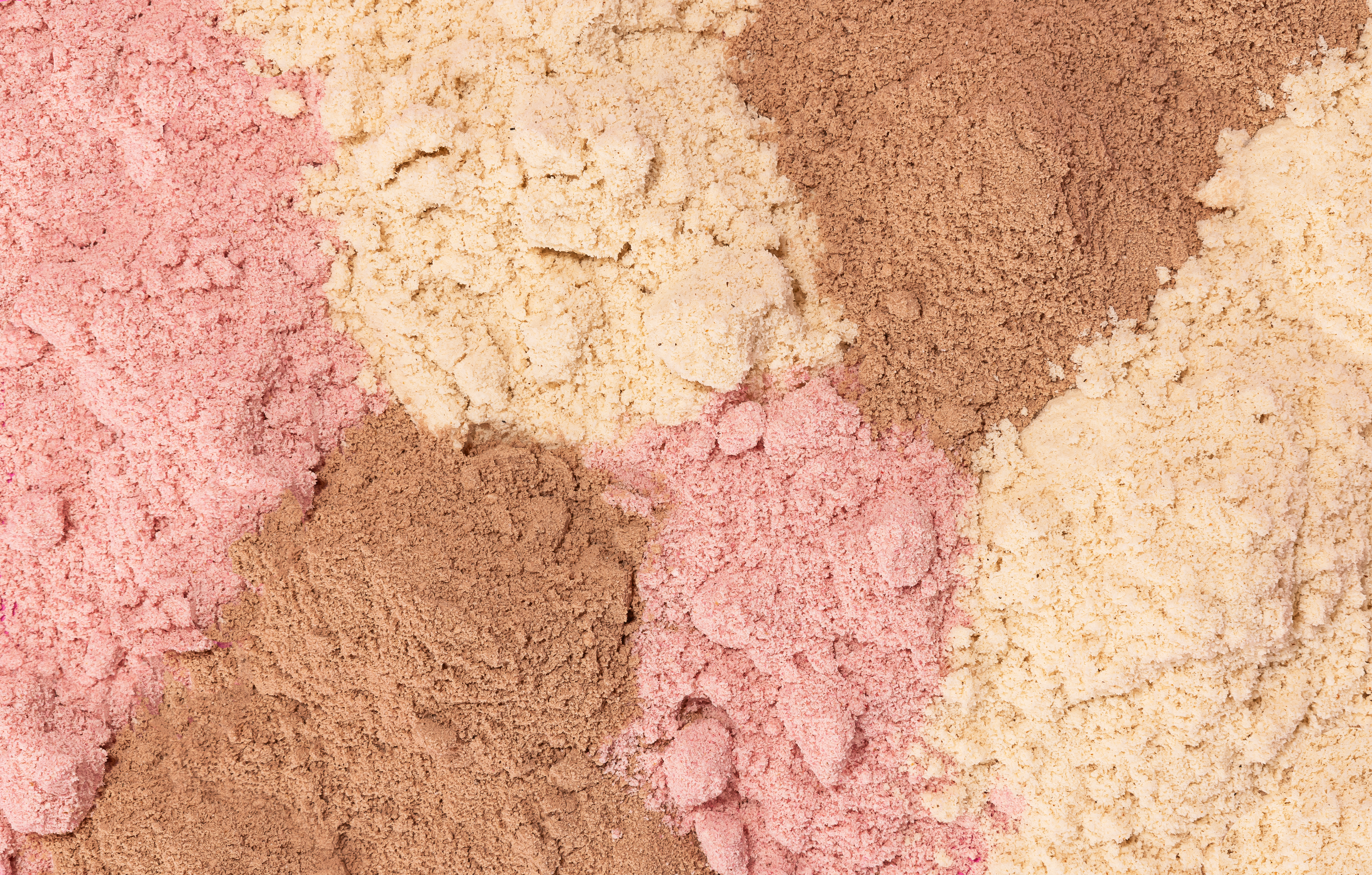 A close-up of various colored protein powders mixed together.