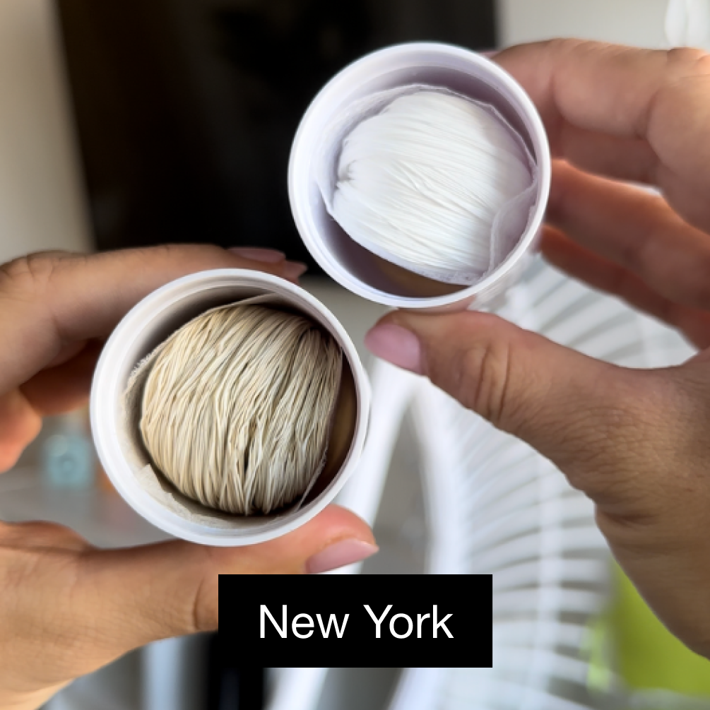 Two hands holding opened capsules with paper-like textures inside.