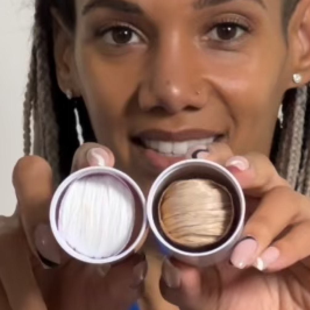 Person holding two small containers with white and beige threads.