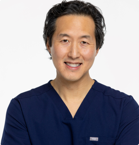 Person smiling in a navy blue scrub top against a white background.