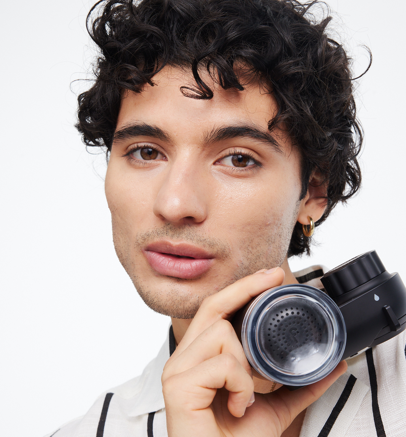 Person holding a black coffee grinder close to their face.