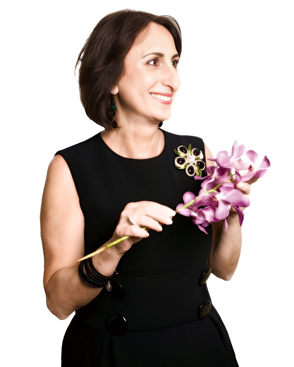A smiling woman in a sleeveless black dress holds a stalk of purple orchids against a white background.