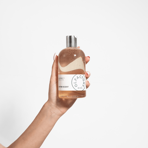 Hand holding a clear bottle with silver cap.