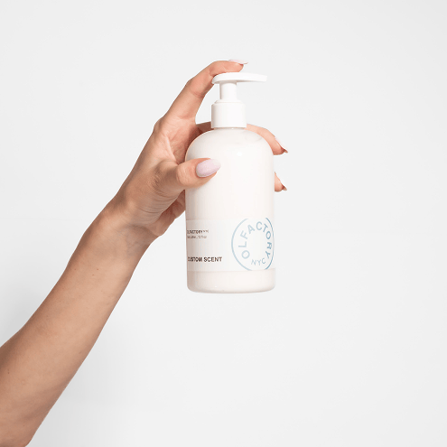 Hand holding a white pump bottle with a circular label.
