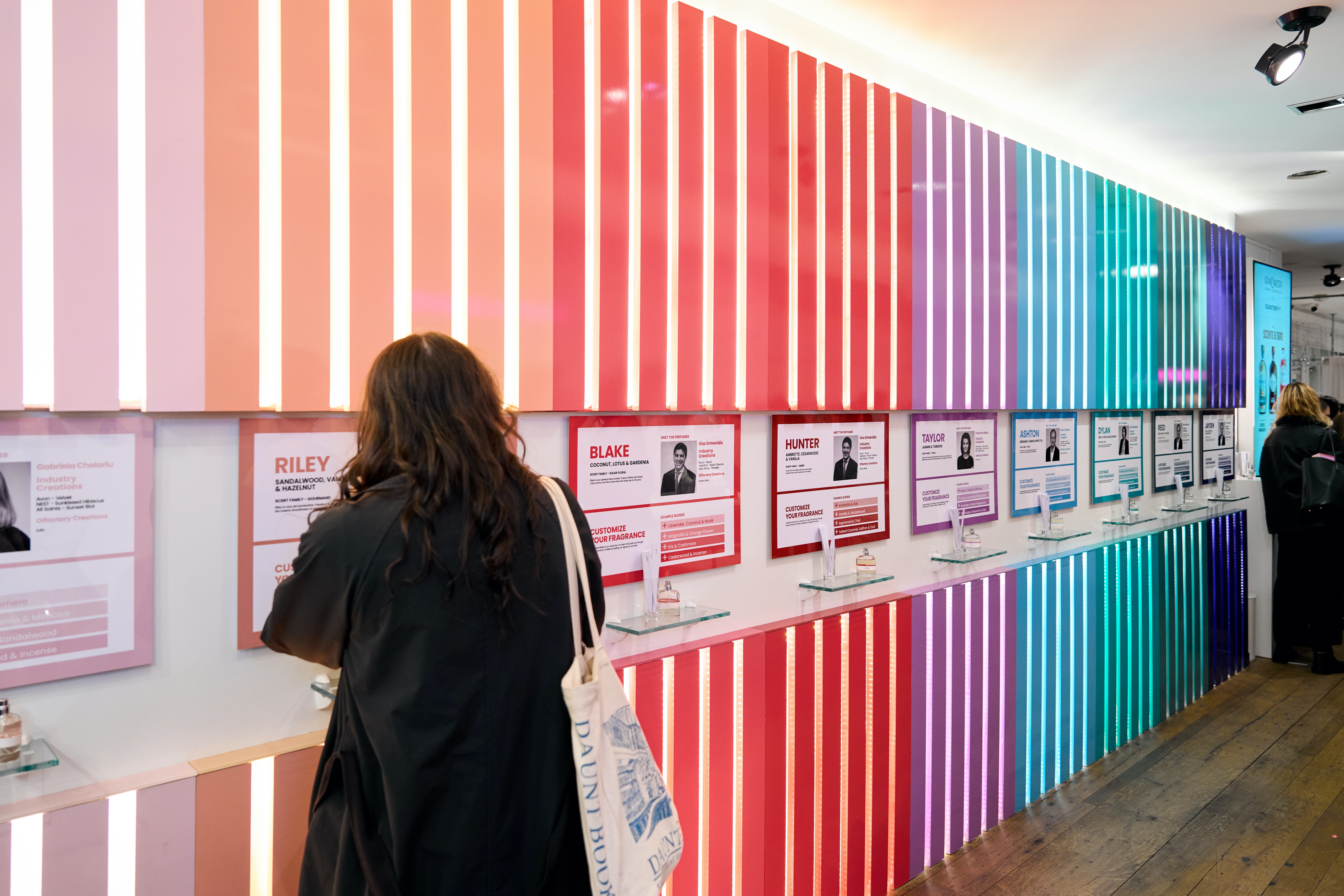 People viewing colorful display panels with fragrance information and samples.