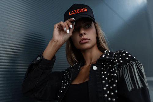 A person wearing a studded jacket and a hat with 'LAZERUS' written on it in red.