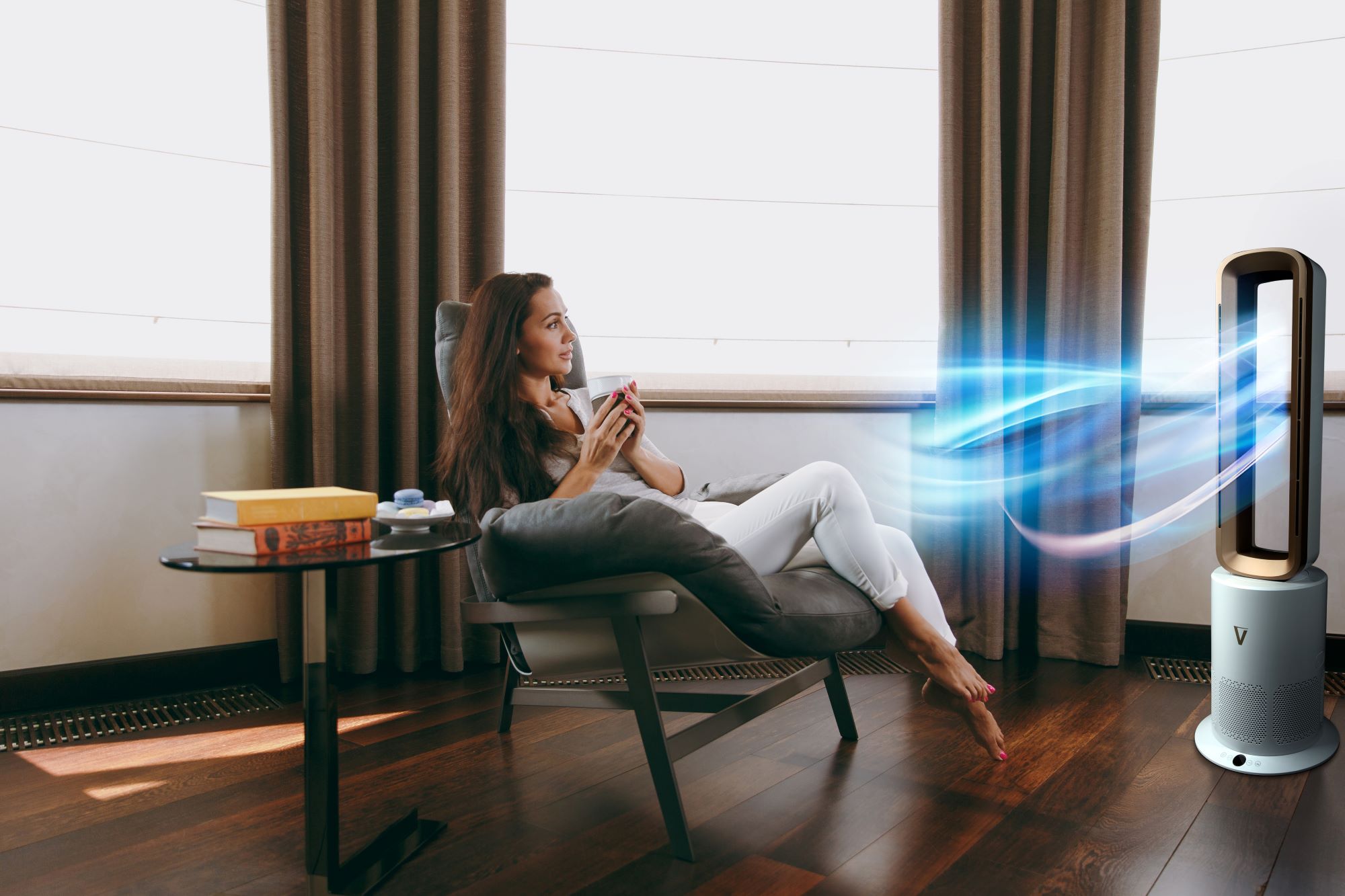 Woman relaxing in a chair with a cup, next to a modern air purifier.