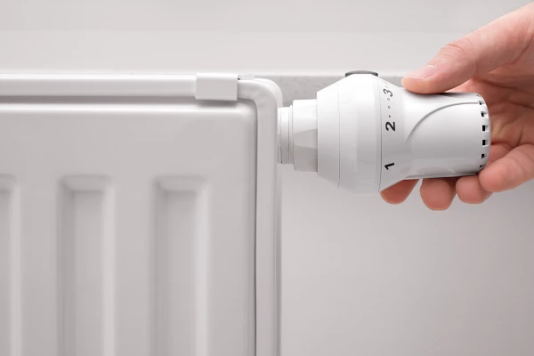 Hand adjusting a radiator thermostat.