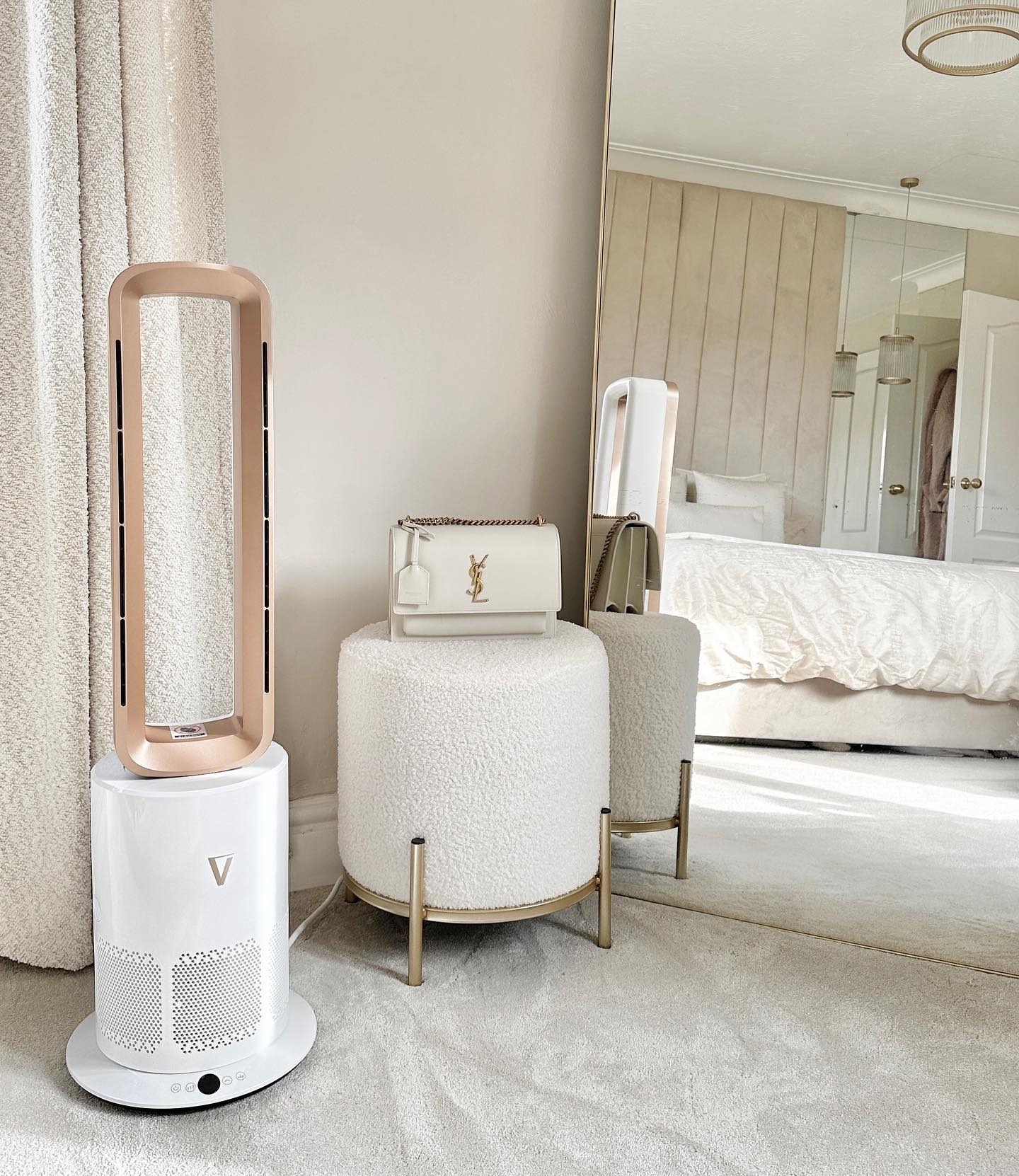 Air purifier, white stool with bag, and mirror in a beige room.