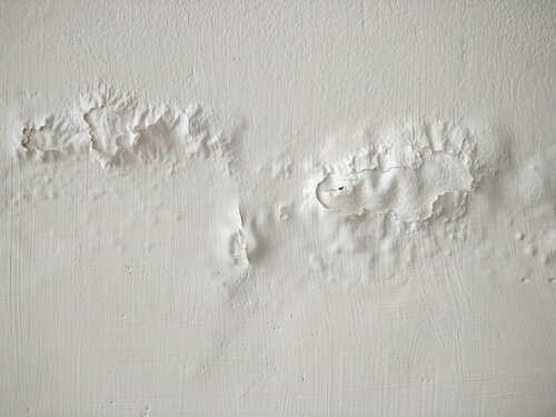 White wall with peeling paint and visible texture.