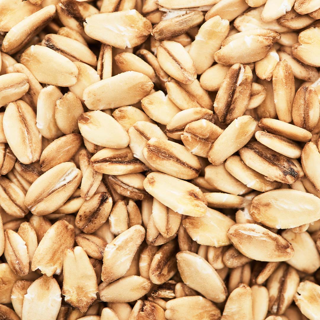 A close-up, overhead shot of a pile of uncooked rolled oats.