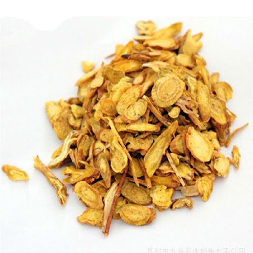 A pile of thinly sliced, dried yellow roots or herbs on a white surface.