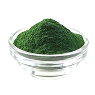A small clear glass bowl filled with a mound of fine dark green powder on a white background.