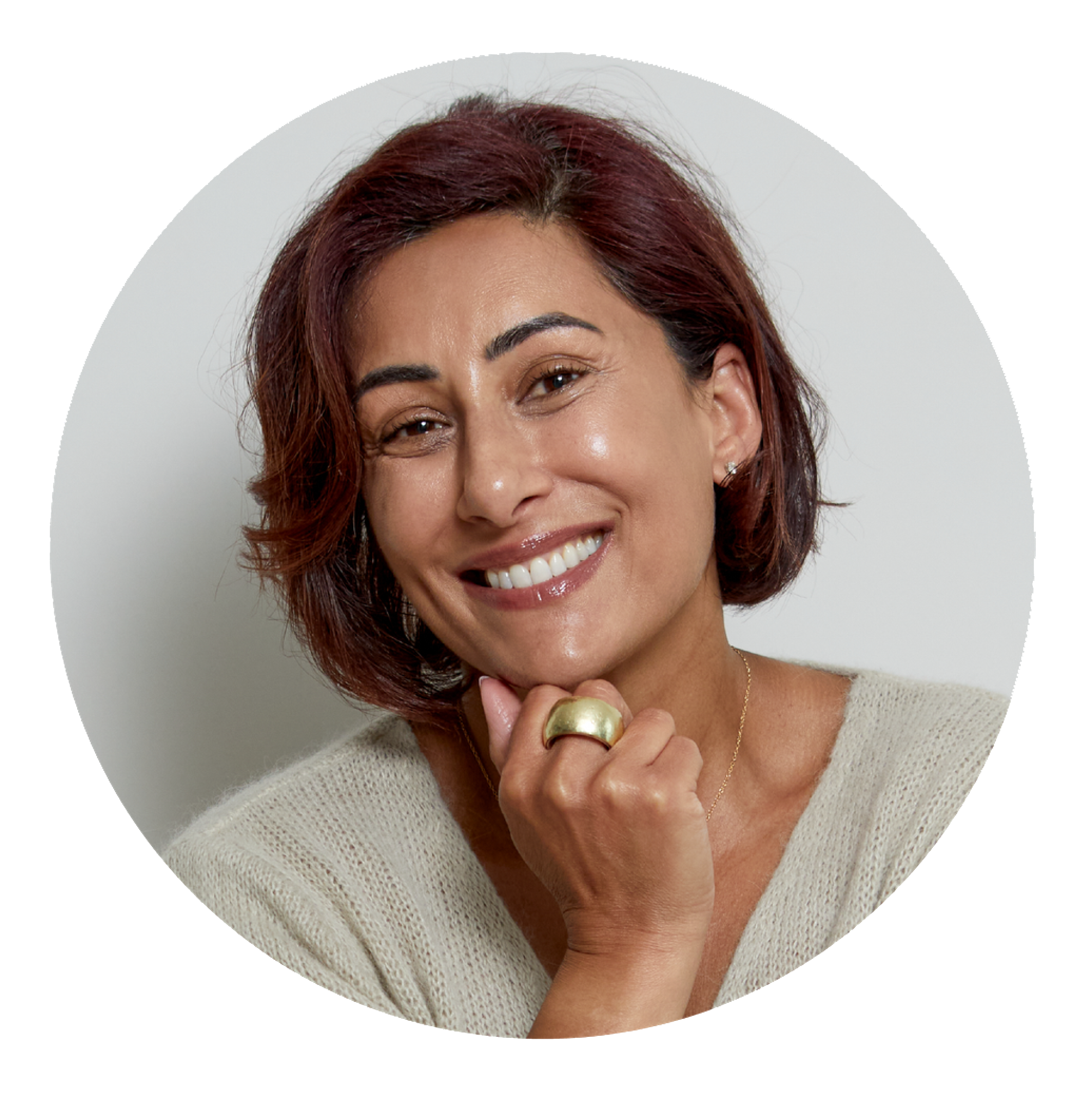 A circular portrait of a smiling woman with reddish-brown hair resting her chin on her hand.