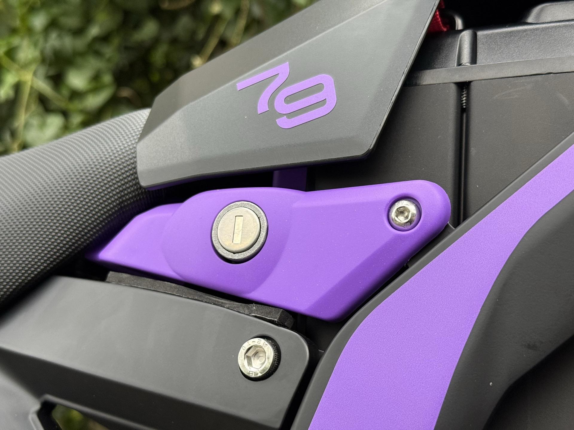 Close-up of a purple and black motorcycle part with a keyhole.