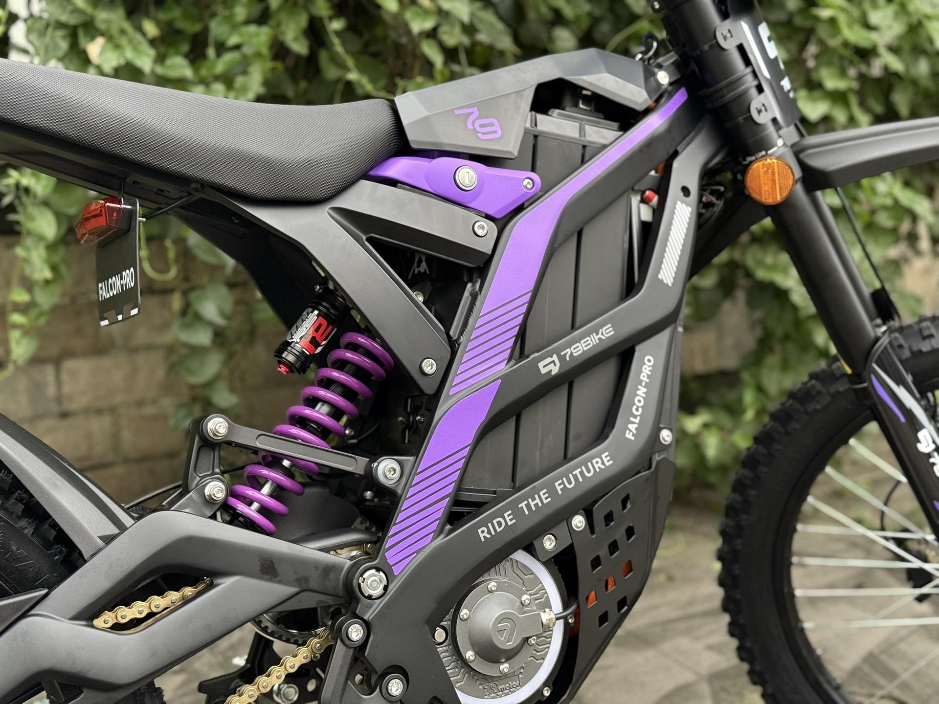 Close-up of a black and purple electric bike with visible suspension and branding.