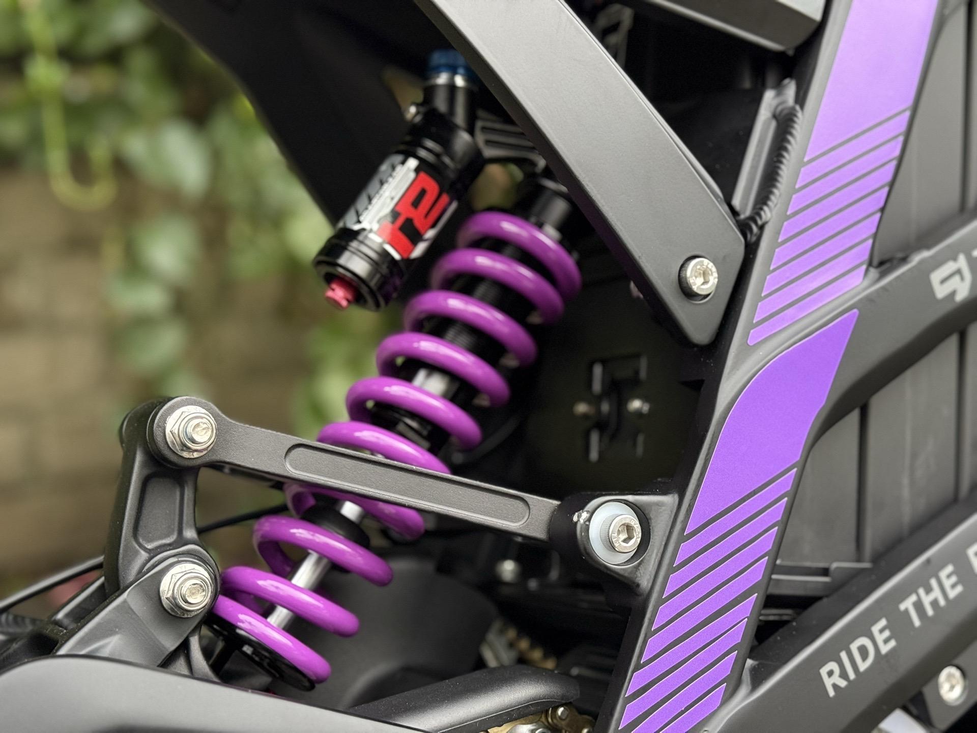 Close-up of a purple coil spring on a mechanical structure.