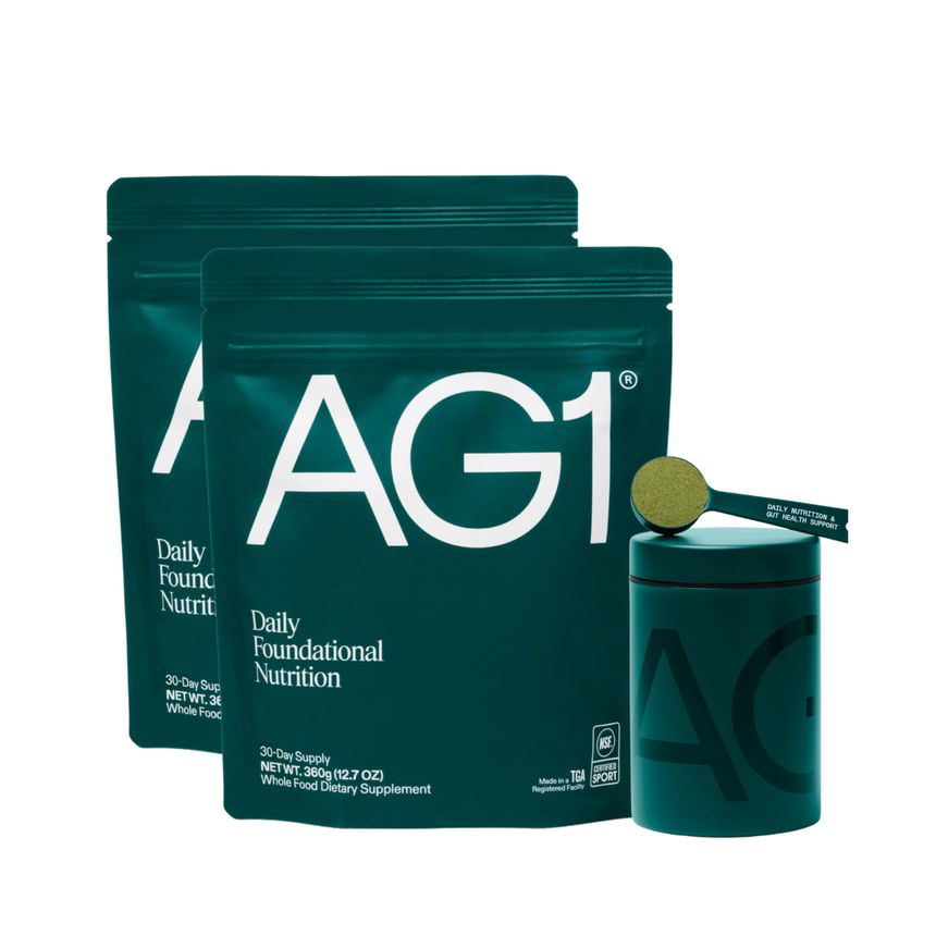 Two pouches and a canister of AG1 Daily Foundational Nutrition with a scoop of green powder.