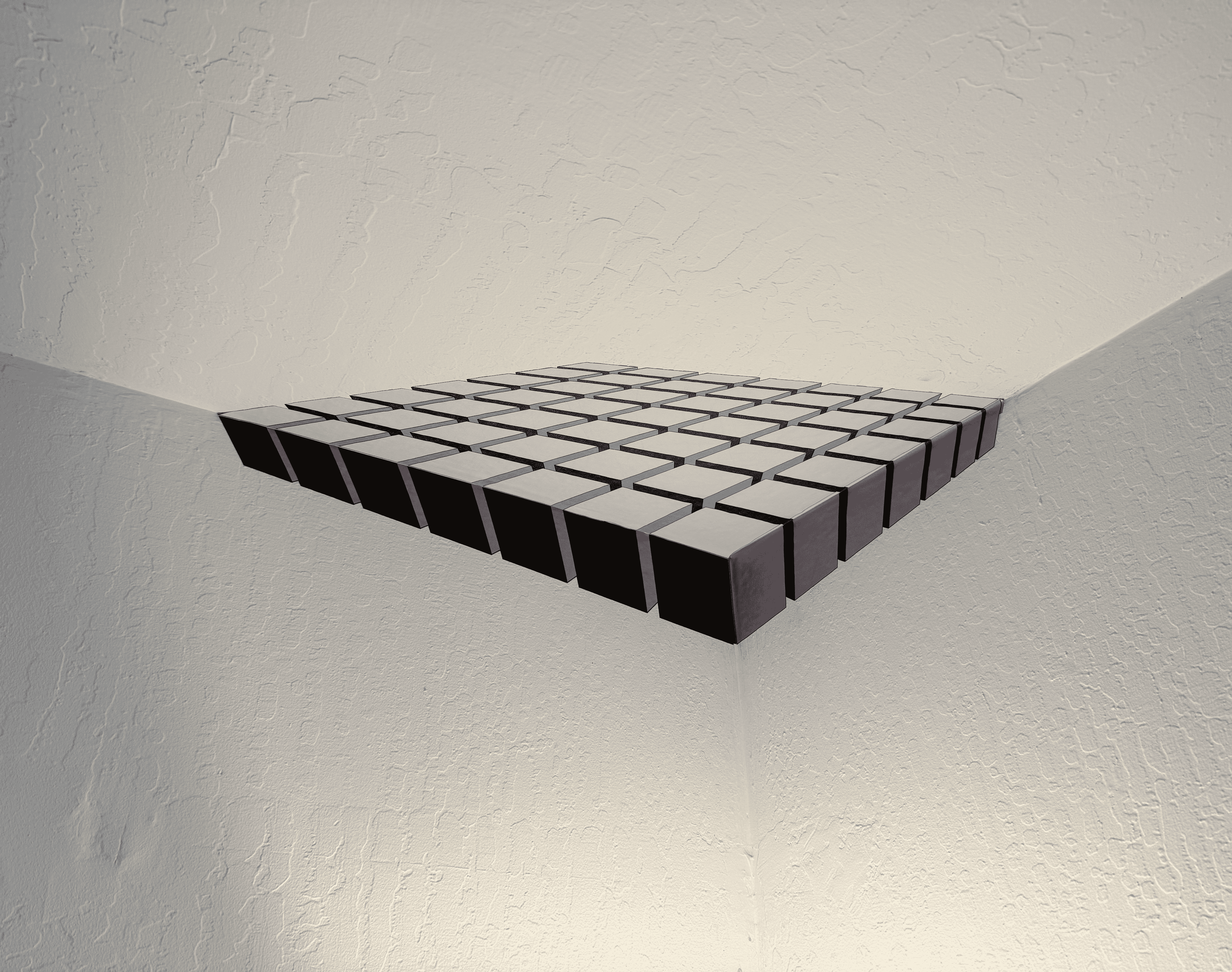 Floating black cubes arranged in a grid pattern on a textured white wall.