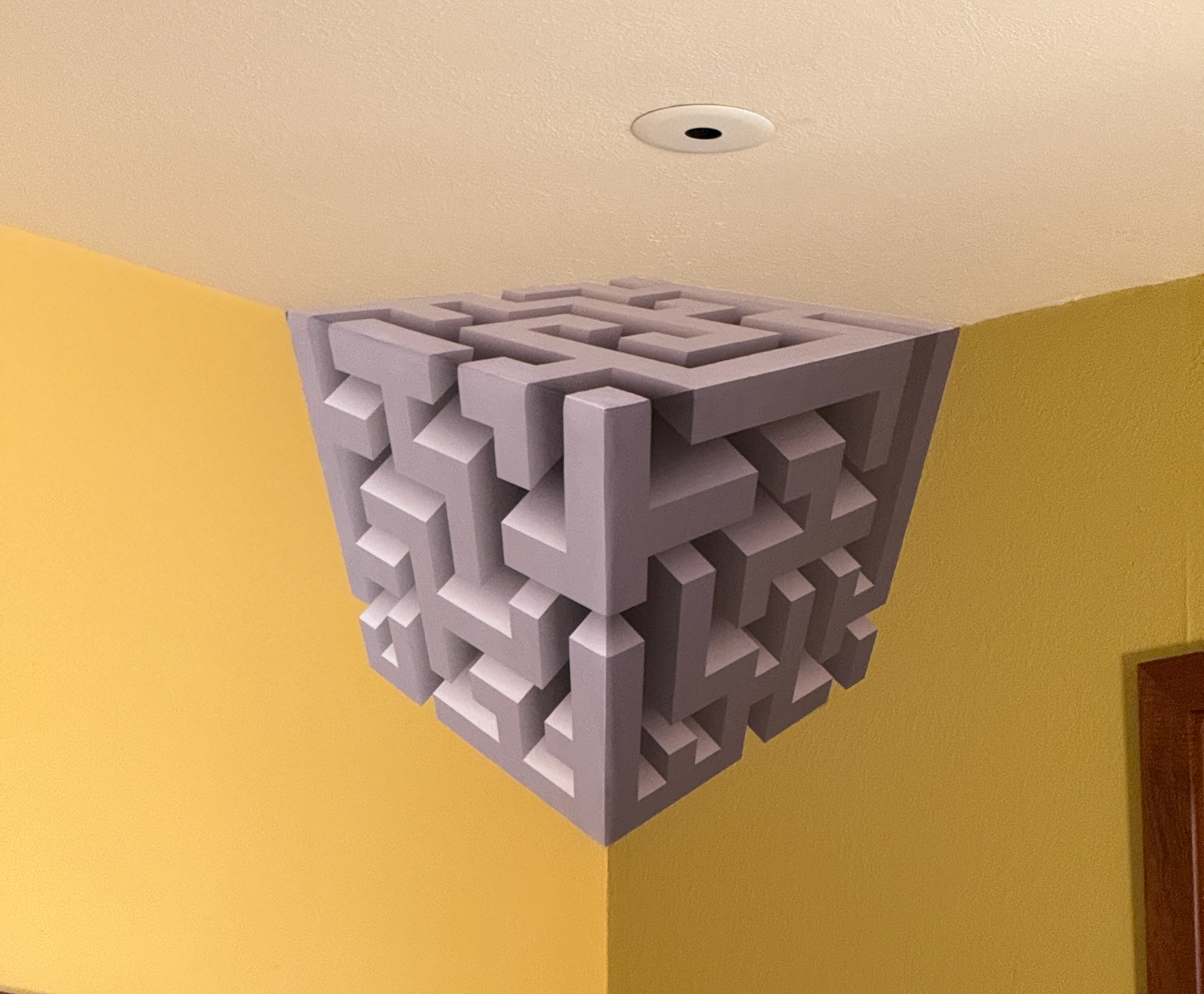 Geometric 3D maze-like structure attached to a ceiling corner.
