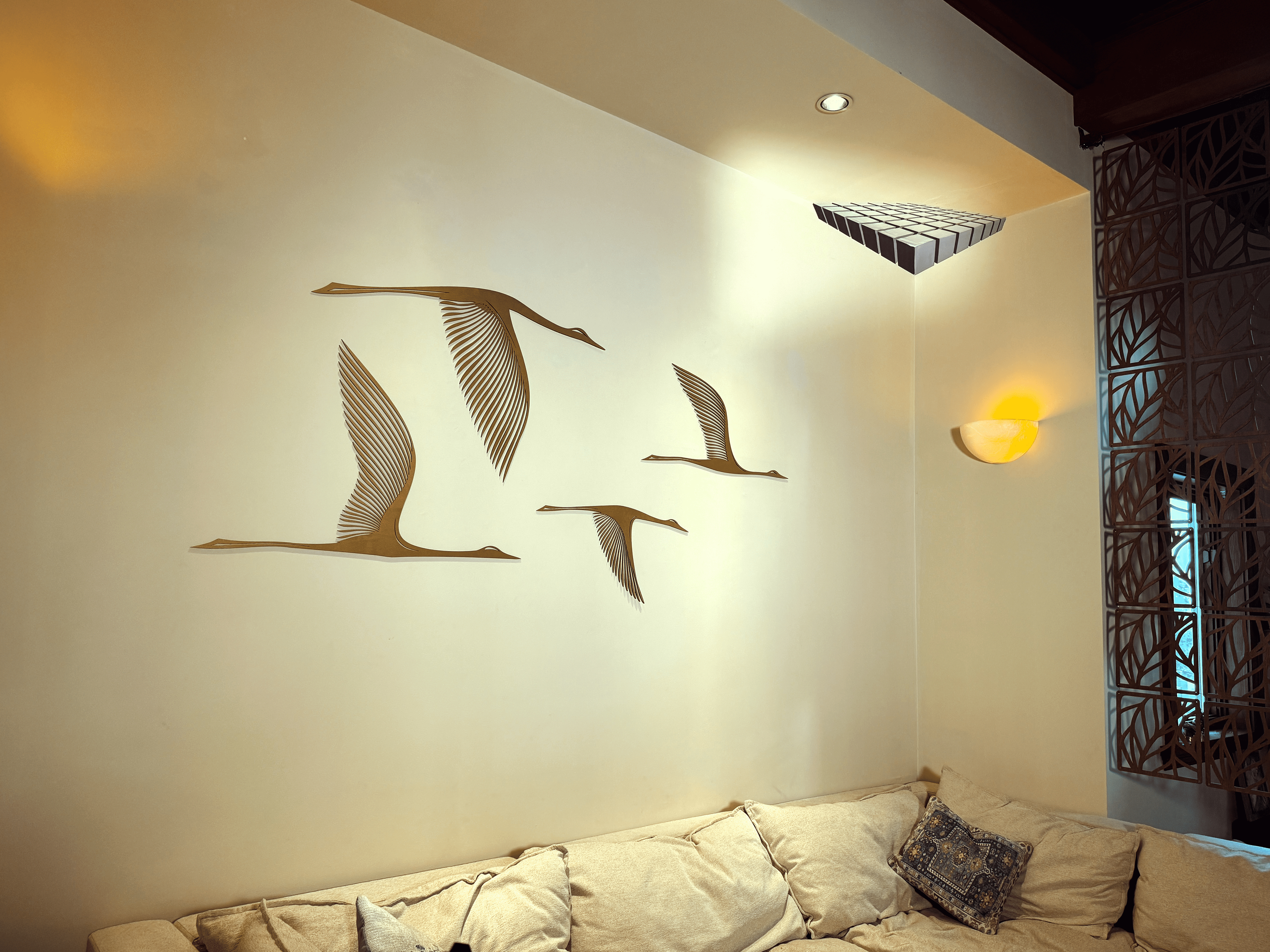 Wall art of flying birds above a beige sofa with cushions.