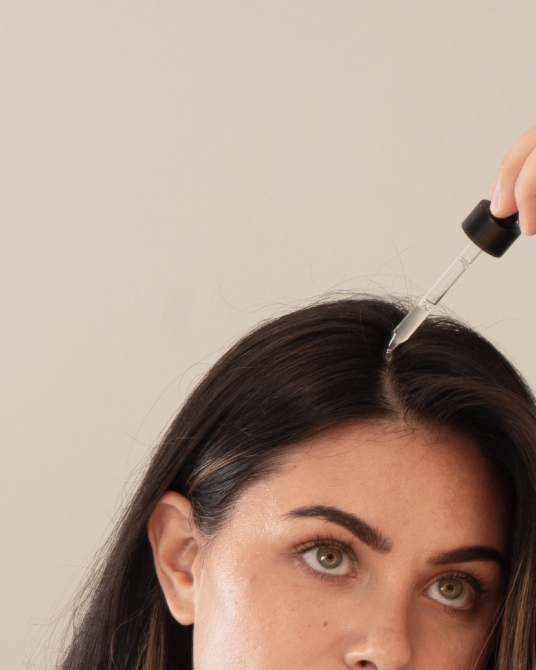 Person applying liquid to scalp with a dropper.