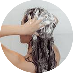 A person with long dark hair lathers it with shampoo in a circular frame.