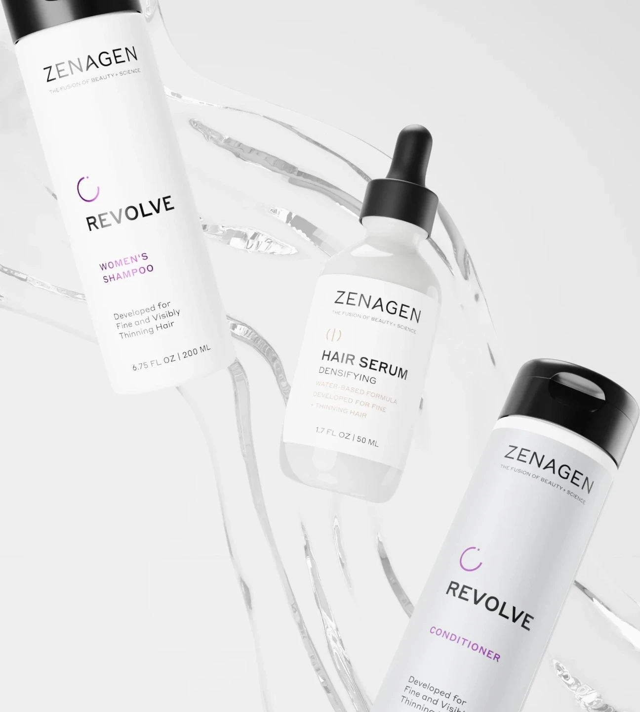 Three bottles of Zenagen Revolve shampoo and conditioner displayed on a rock with green leafy plants.