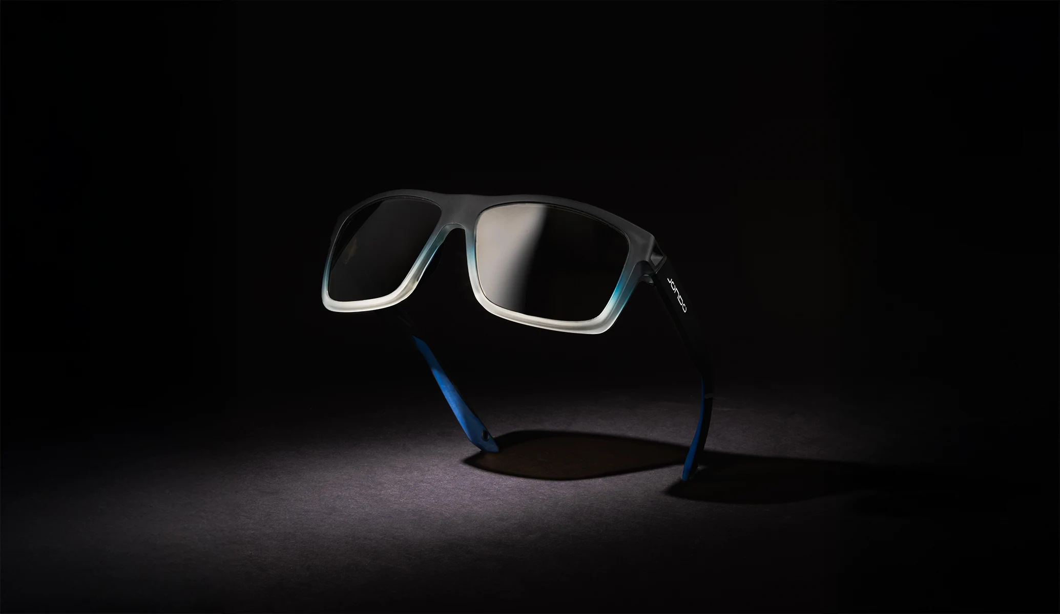 Black sunglasses with blue temples on a dark background.