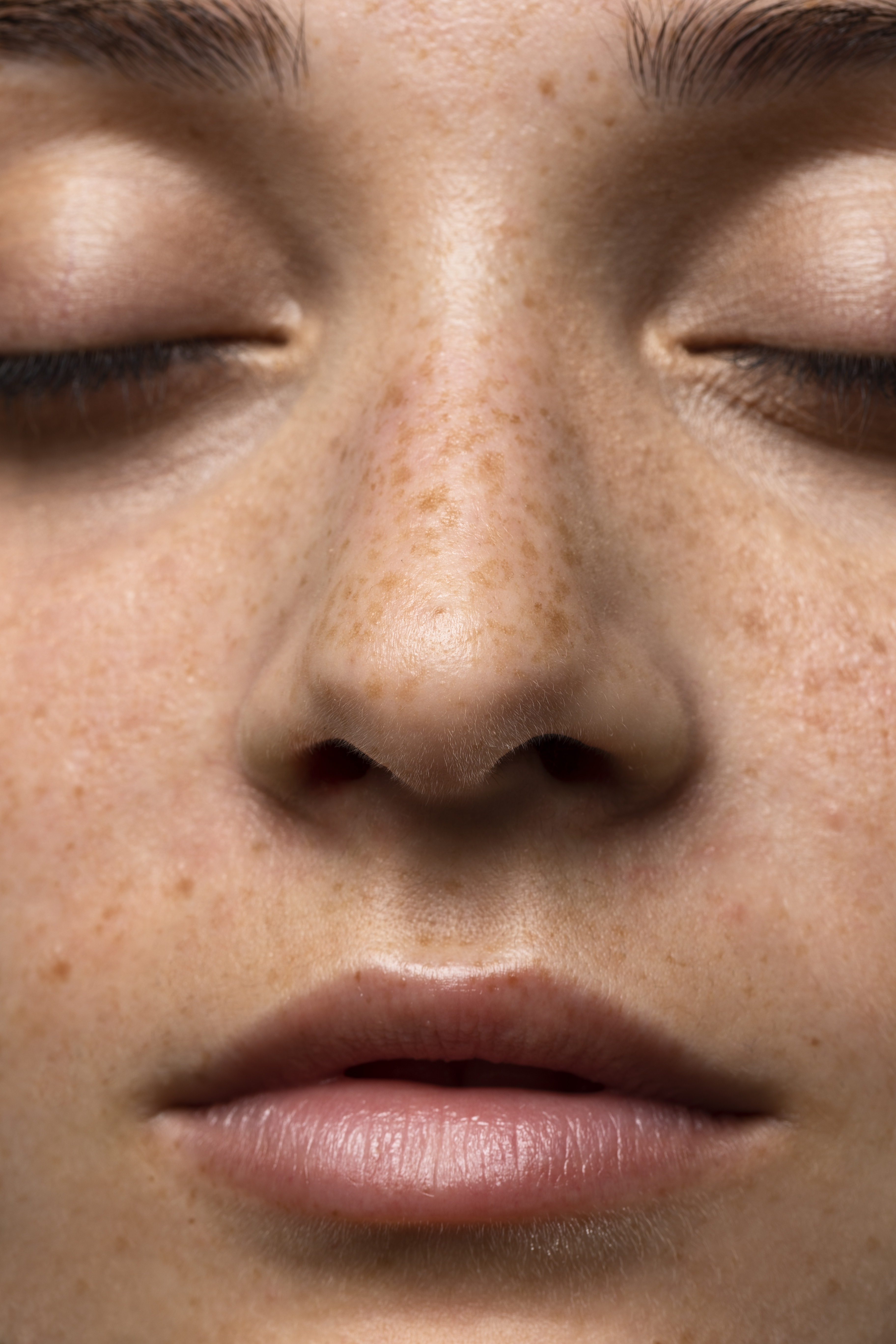 Close-up of a person's face with closed eyes and freckles.