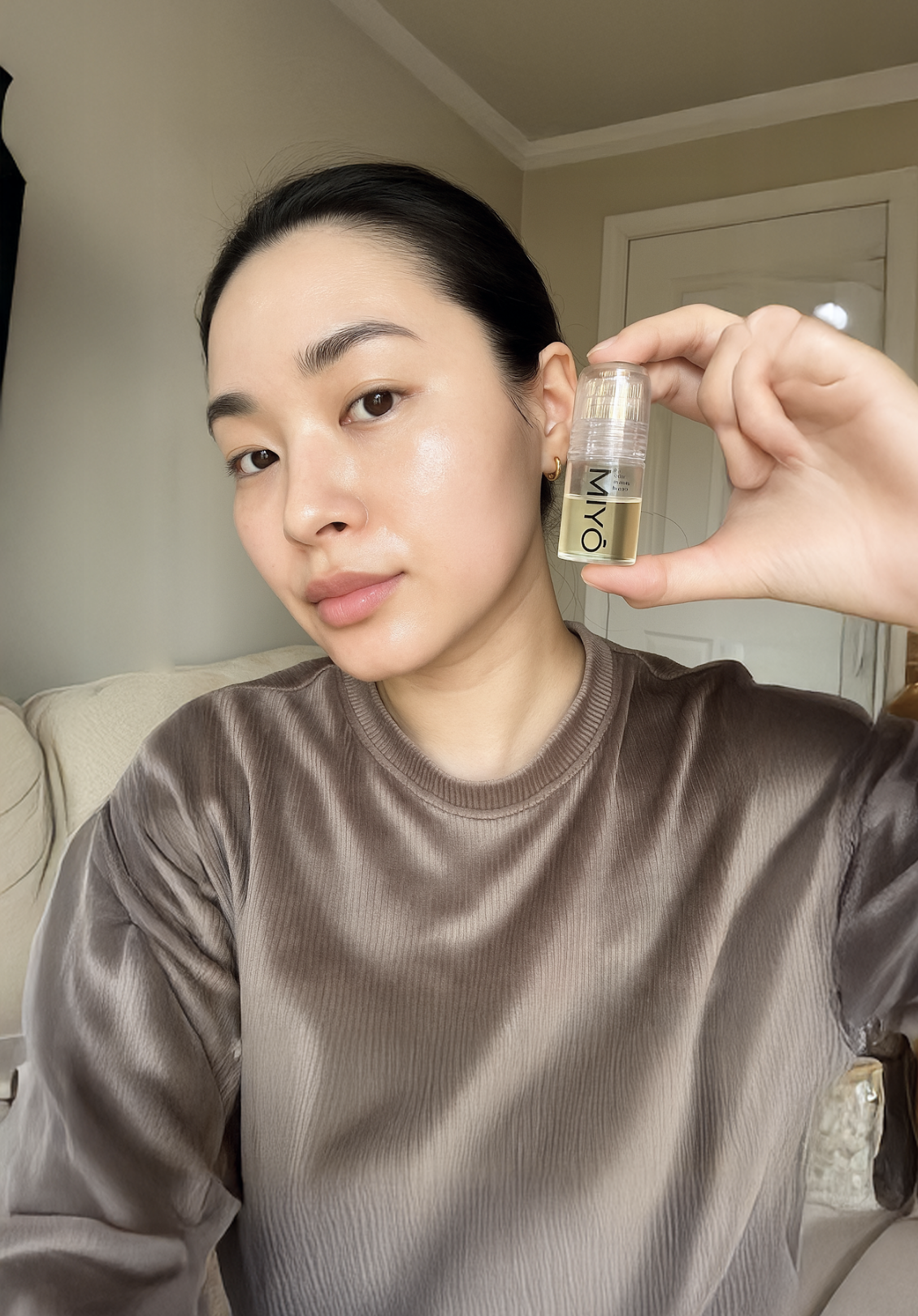 Person holding a small bottle labeled 'MIYO' near their face.