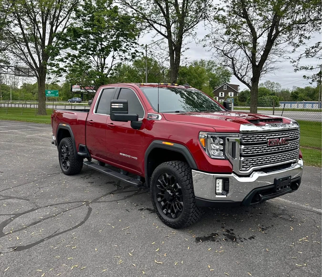 Red pickup truck parked on a paved area with trees in the background.