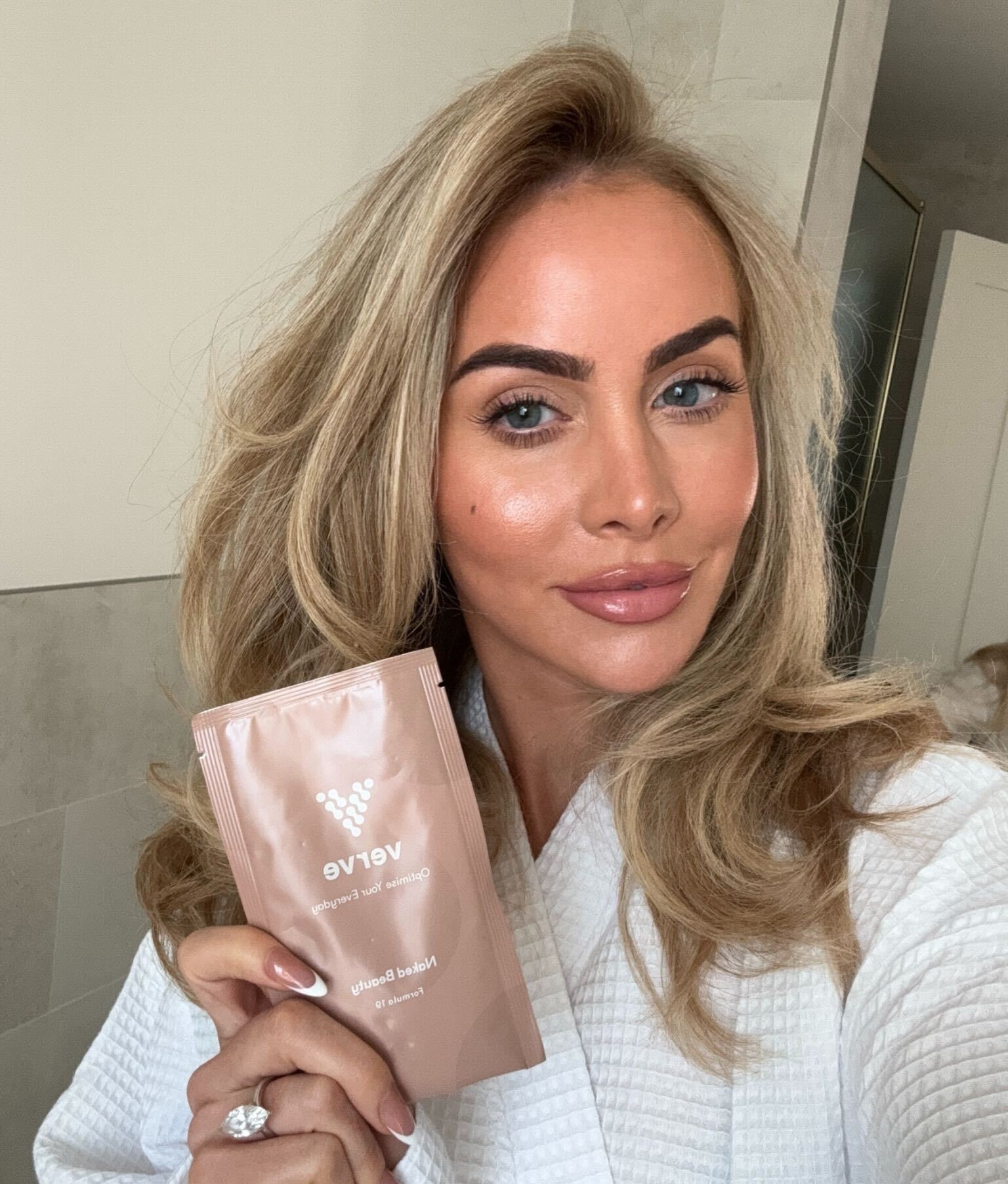 Person holding a Verve product packet, wearing a white robe.
