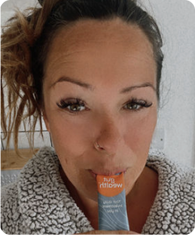 Person in a robe holding a tube labeled 'gut health' to their mouth.
