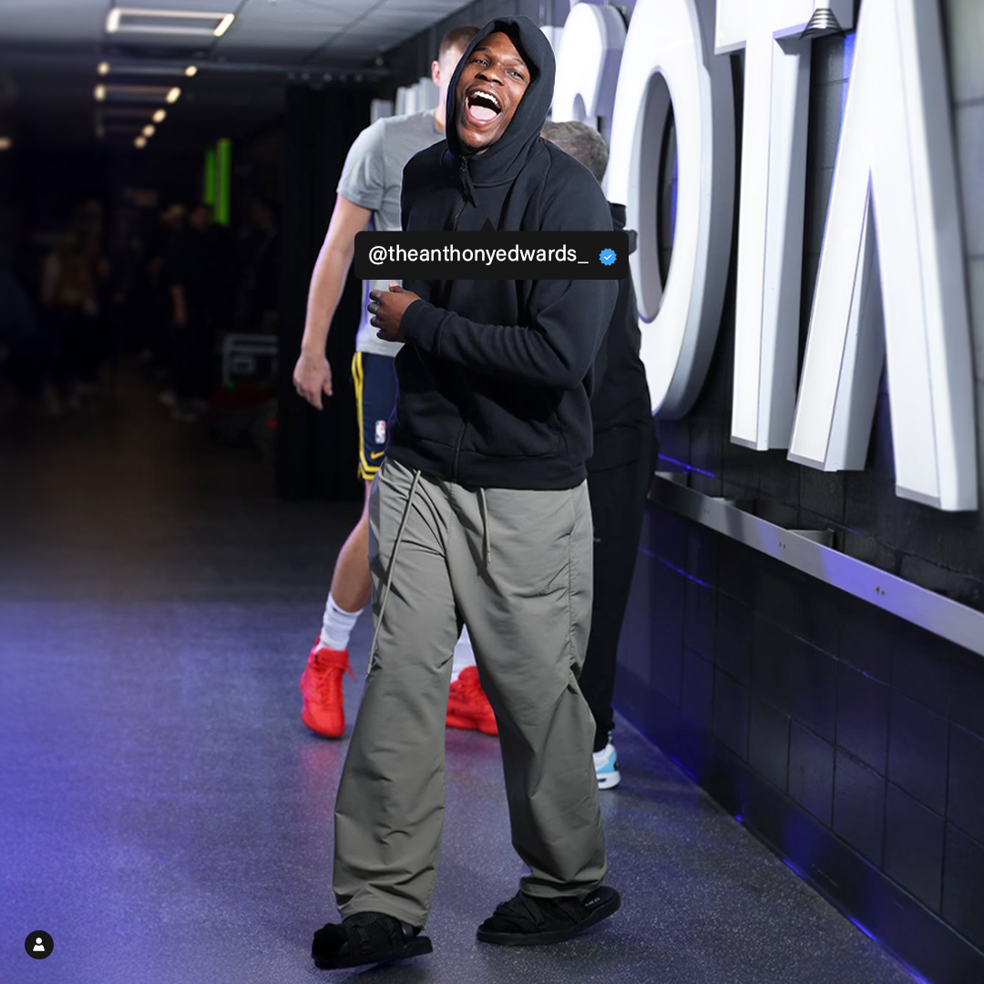 Person in a black hoodie laughing in a hallway.