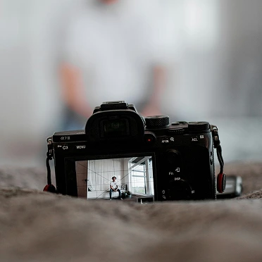 Camera on a surface with a person visible in its display screen.