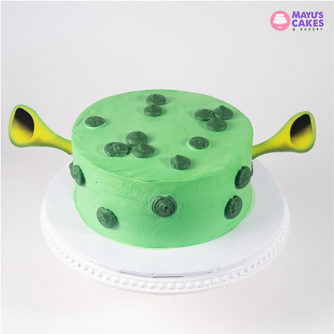 Green cake with black spots and two yellow-green protrusions on a white stand.