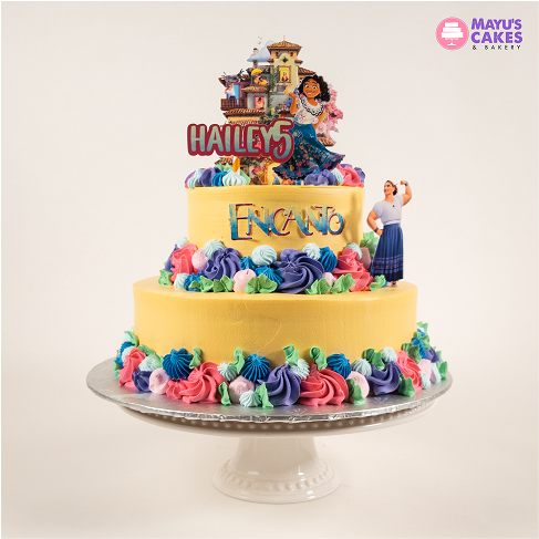 Two-tiered Encanto-themed cake with colorful frosting and character toppers.