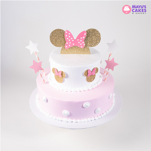Two-tier cake with pink and gold Minnie Mouse decorations and star toppers.