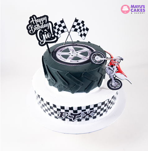 A cake designed like a tire with a toy truck and 'Felicidades Roberto' topper.